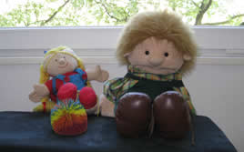 Teddyb&auml;r und Handpuppe mit blauem Ball auf Holzregal
